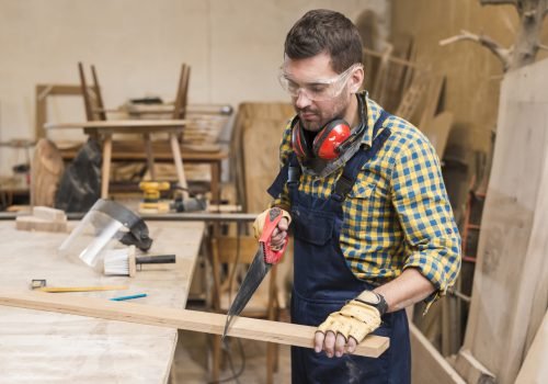 close-up-handyman-sawing-long-wooden-plank