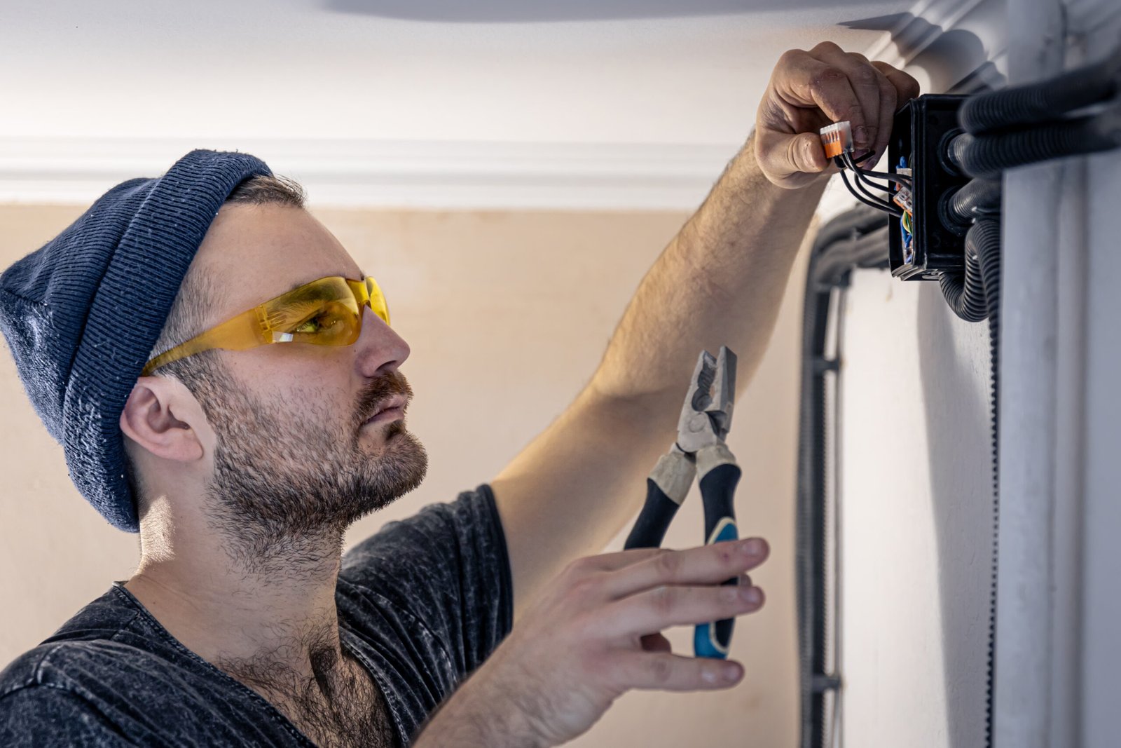 Attractive male electrician repairing an outlet, installing an outlet indoors.